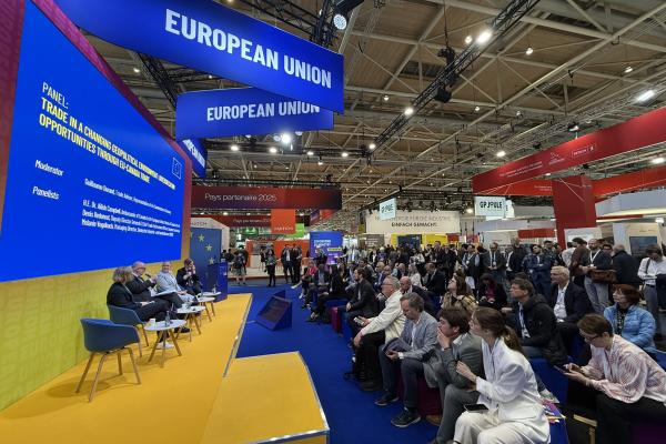 A large audience watches a panel of speakers on stage.